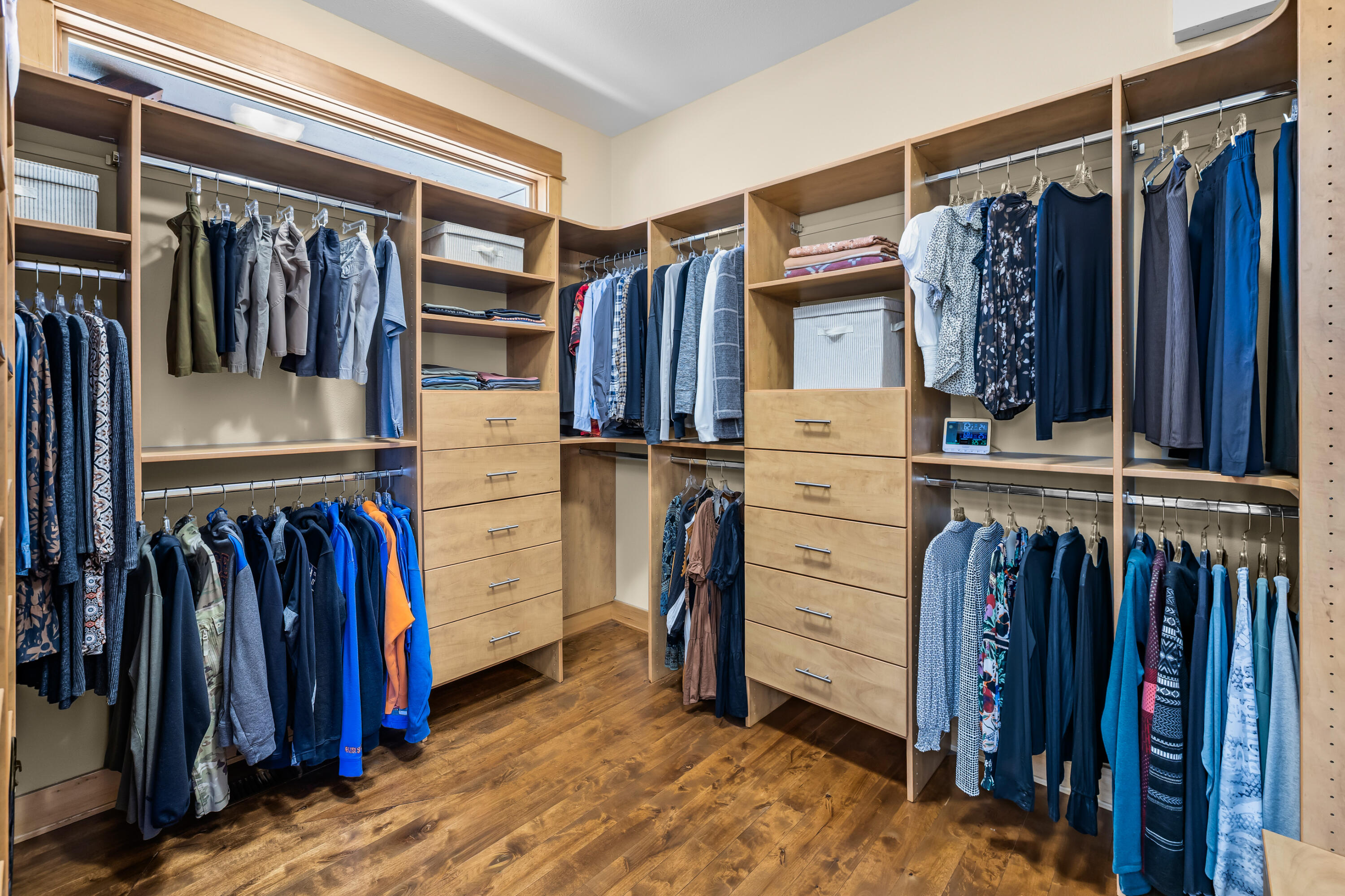 64145 Hunnell Road Bend, OR 97703 - Photo 22 of 65 The primary suite includes a spacious walk-in closet with built-in drawers, open shelving, hanging space and wood floors, offering a well-organized extension of the private suite.