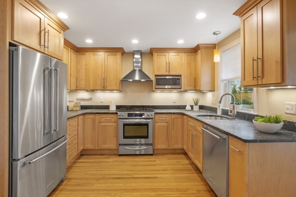 2 Reed St Court, Unit 2 Cambridge, MA 02140 - Photo 5 of 31 a kitchen with stainless steel appliances granite countertop a refrigerator a sink dishwasher a stove with wooden cabinets and floor