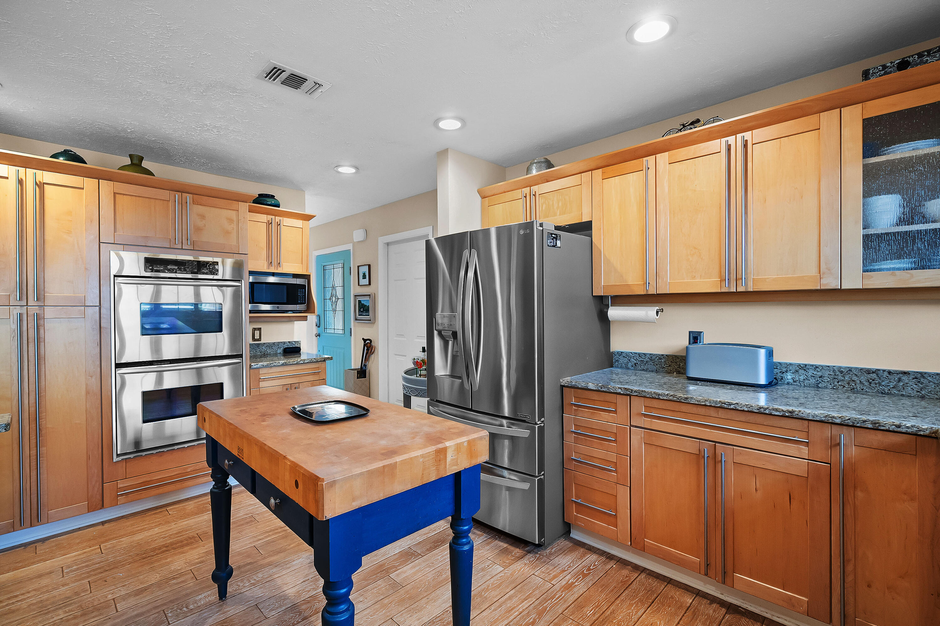 5105 Southeast Matousek Street Stuart, FL 34997 - Photo 17 of 48 a kitchen with stainless steel appliances granite countertop a refrigerator a sink dishwasher and wooden cabinets with wooden floor