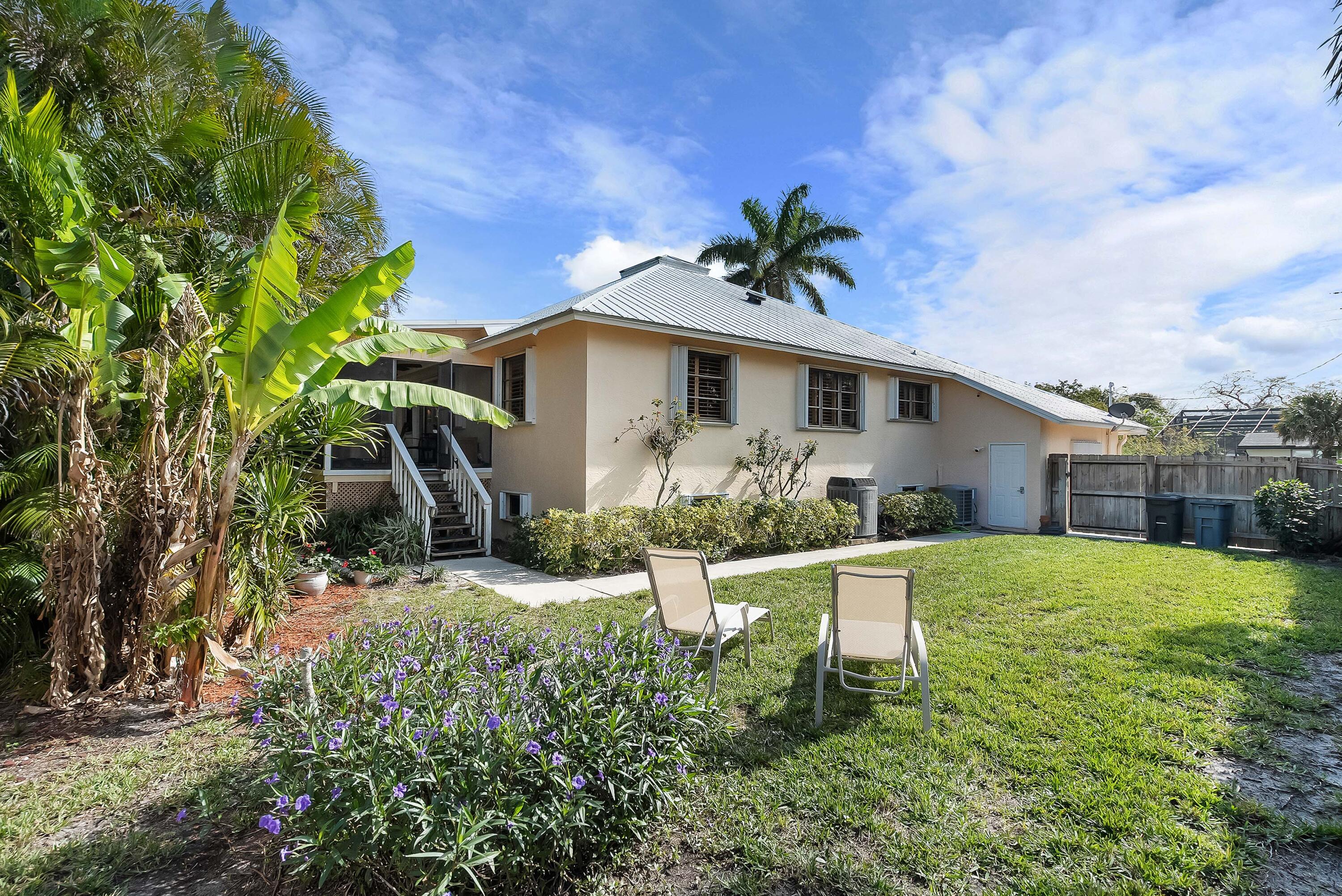 5105 Southeast Matousek Street Stuart, FL 34997 - Photo 31 of 48 a white house with a small yard and plants