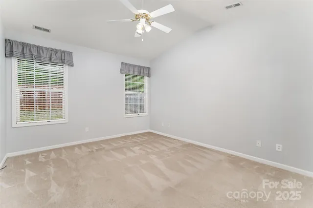en empty room with windows and ceiling fan