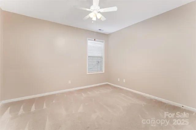 an empty room with a window and a ceiling fan
