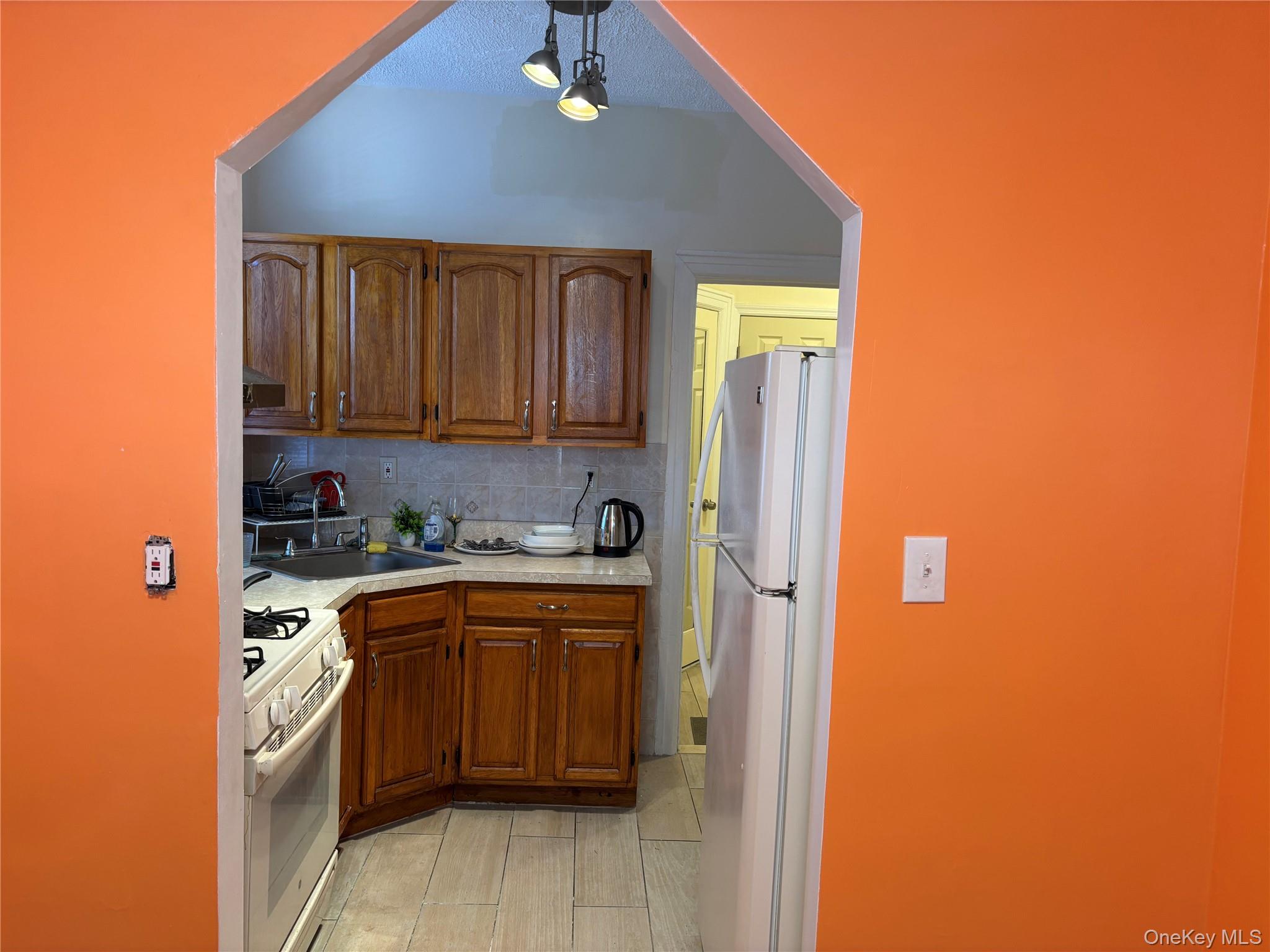 1004 Lenox Road Brooklyn, NY 11212 - Photo 4 of 13 Compact kitchen featuring wood cabinetry, white appliances, and a gas range