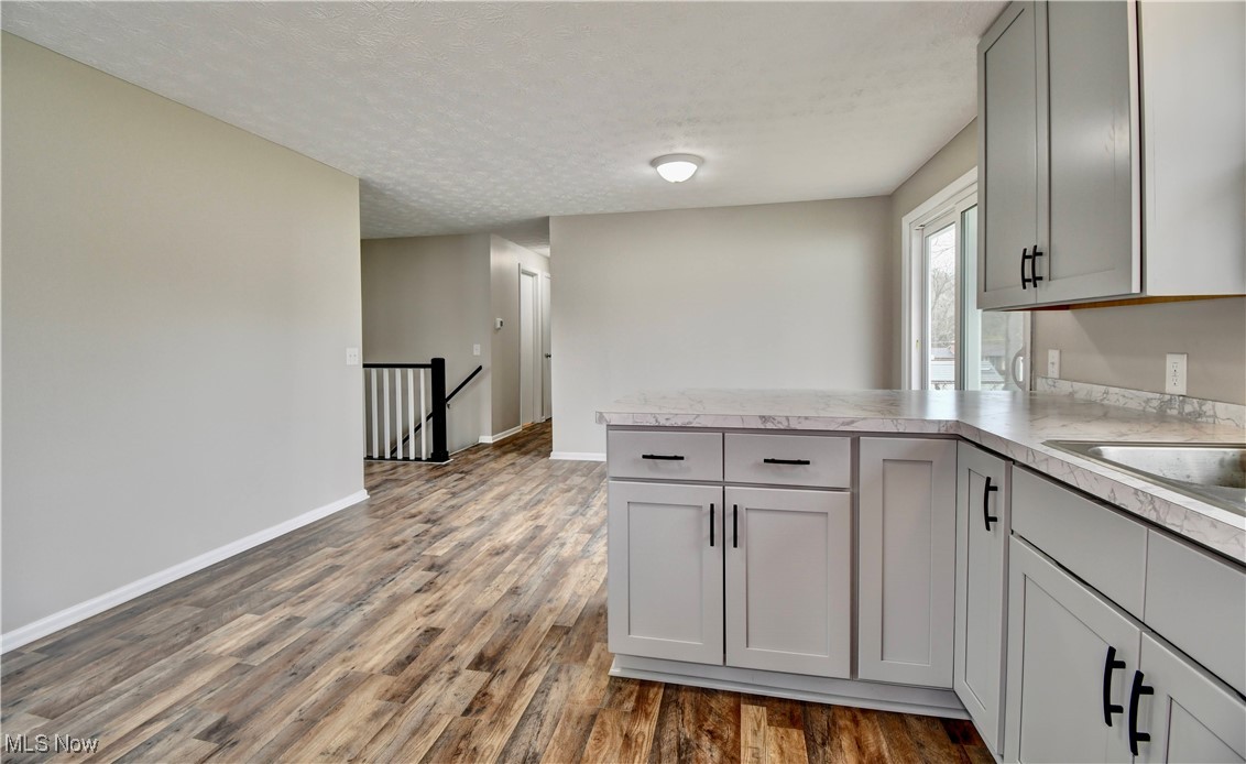 494 Moore Road Akron, OH 44319 - Photo 11 of 30 Kitchen featuring a peninsula, gray cabinets, wood finished floors, light countertops, and baseboards