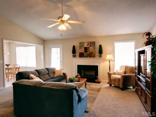 5633 Lighthall Lane Raleigh, NC 27604 - Photo 2 of 11 Family room with cathedral ceiling, ceiling fan, fireplace, and plant ledge.