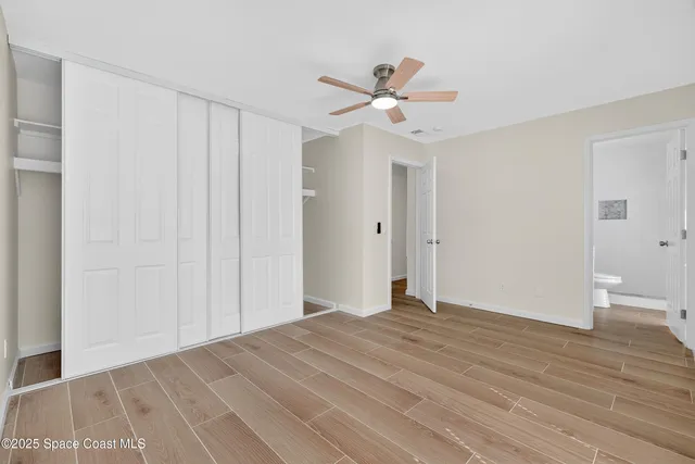 an empty room with wooden floor ceiling fan and windows