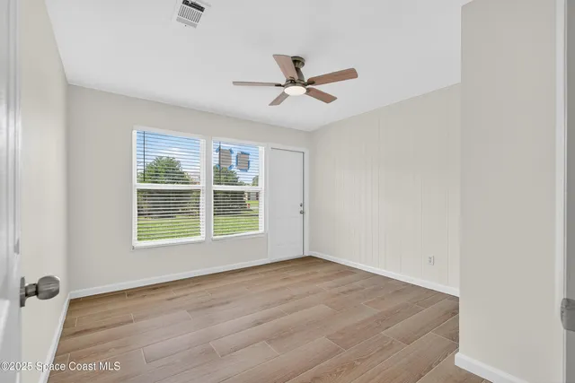 a view of a room with wooden floor a ceiling fan and closet area