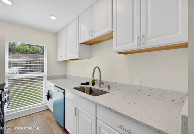a kitchen with stainless steel appliances granite countertop white cabinets and a sink