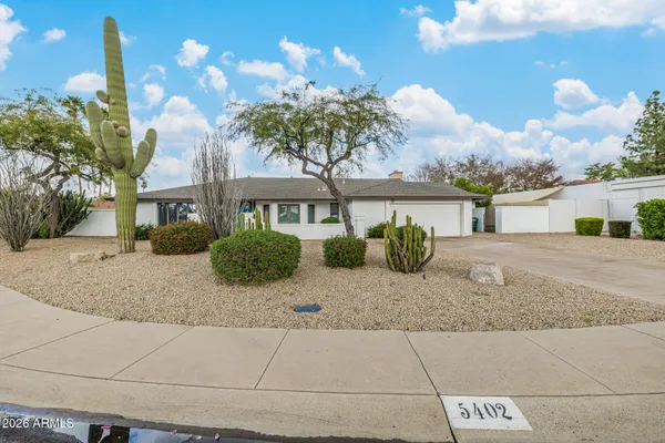 a front view of a house with a yard and potted plants