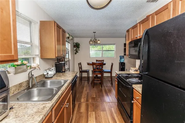 a kitchen with granite countertop a stove a sink a dining table and chairs
