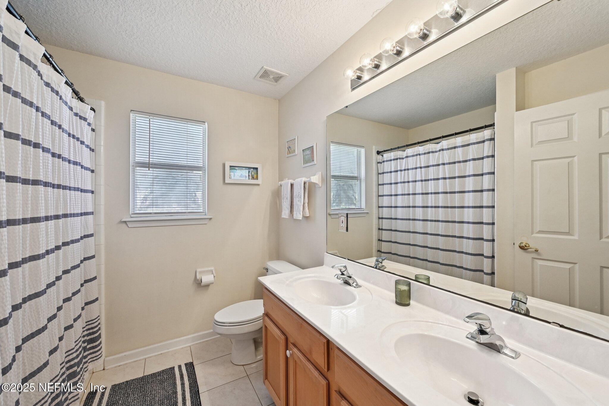 1862 Sentry Oak Court Fleming Island, FL 32003 - Photo 19 of 83 a bathroom with a double vanity sink toilet and shower