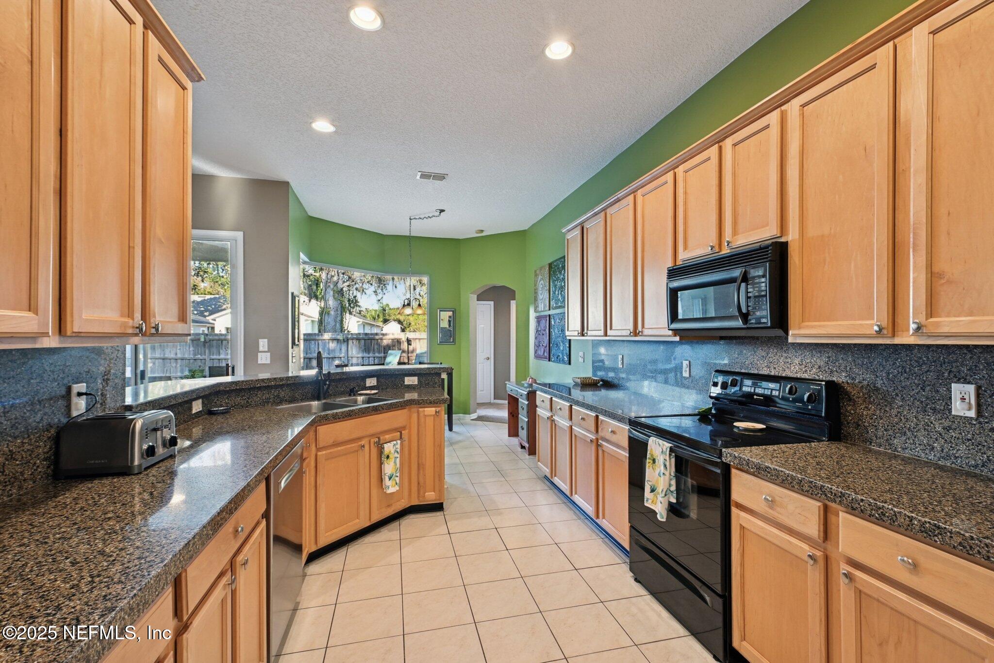 1862 Sentry Oak Court Fleming Island, FL 32003 - Photo 35 of 83 a kitchen with stainless steel appliances granite countertop a stove a sink and a microwave