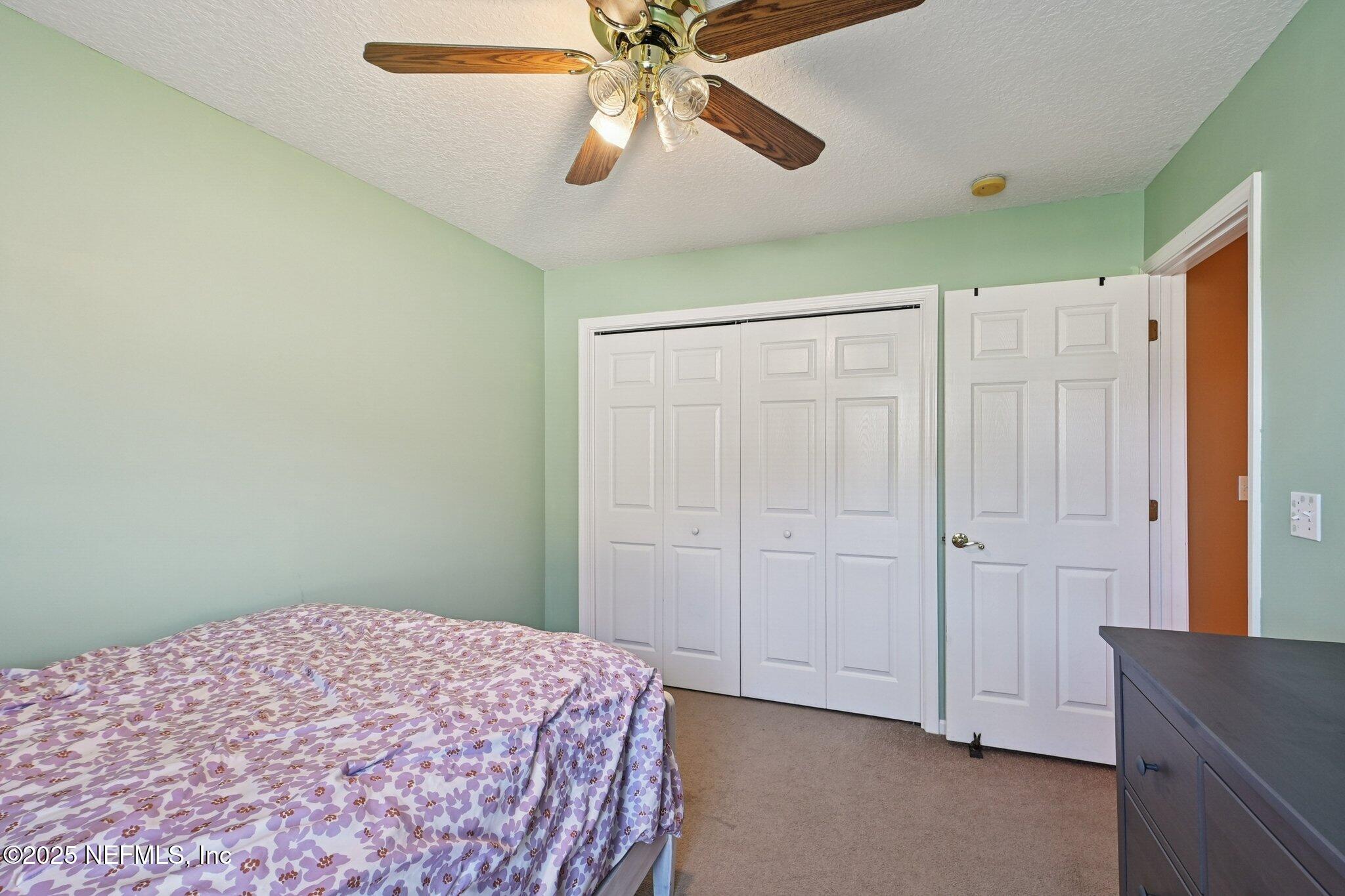 1862 Sentry Oak Court Fleming Island, FL 32003 - Photo 43 of 83 a bedroom with a bed and a chandelier fan