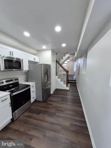 a view of kitchen with cabinets stainless steel appliances and wooden floor