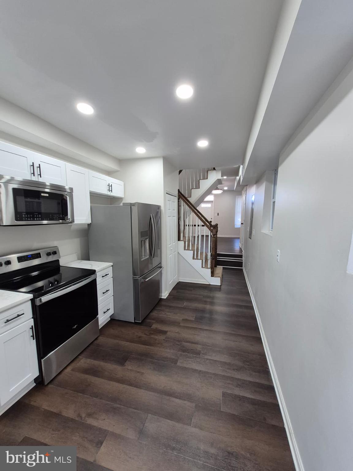 a view of kitchen with cabinets stainless steel appliances and wooden floor
