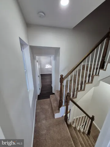 a view of staircase with lots of frames on wall and a window