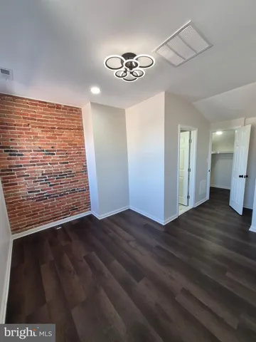 a view of an empty room with wooden floor and a ceiling fan