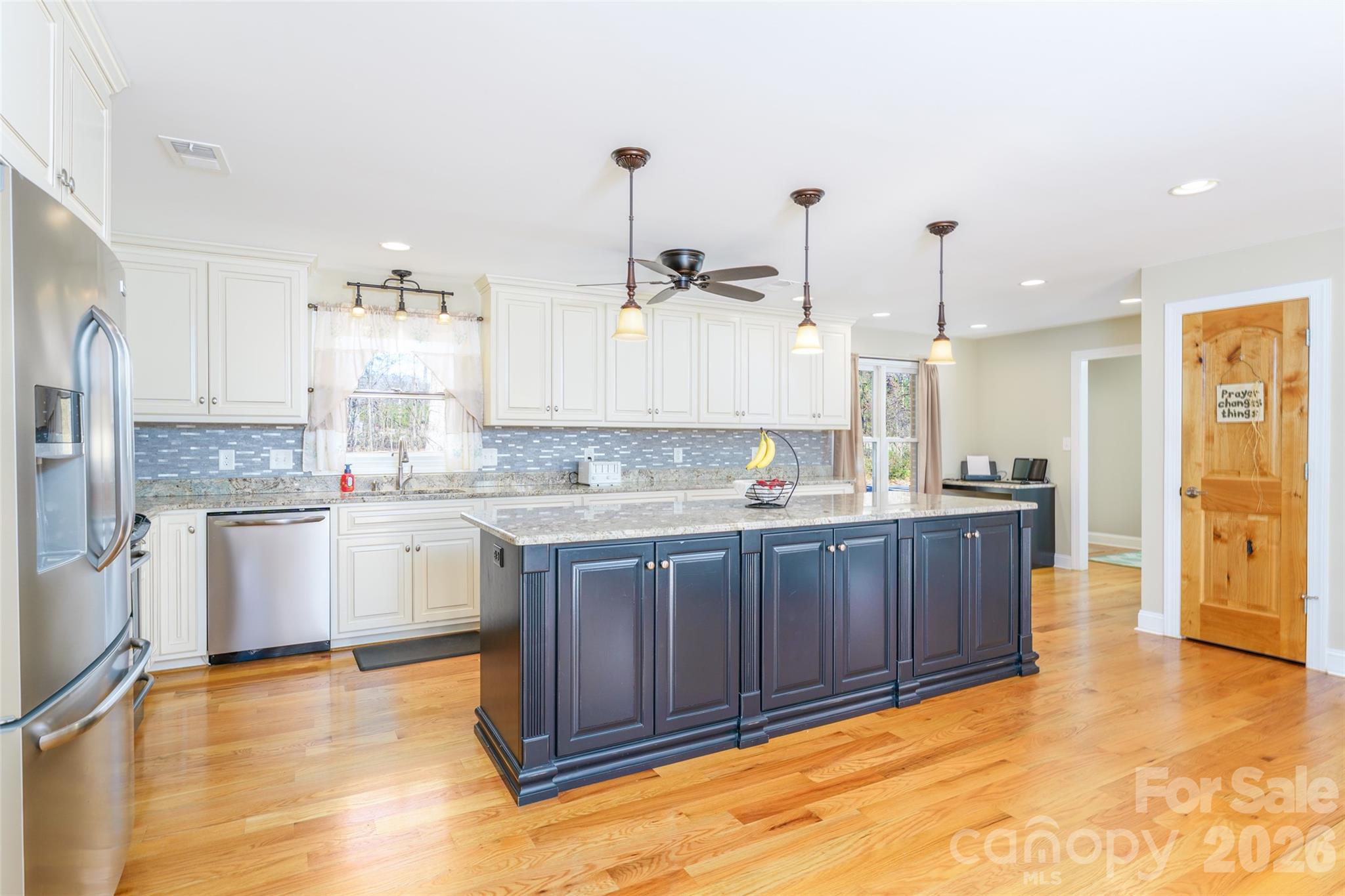 8194 Mallard Road Denver, NC 28037 - Photo 6 of 48 a large kitchen with kitchen island granite countertop a stove a sink a refrigerator and white cabinets with wooden floor
