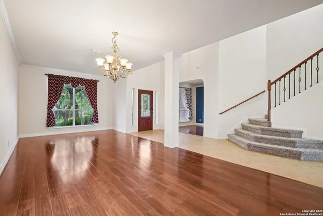 a view of a room with wooden floor chandelier and windows