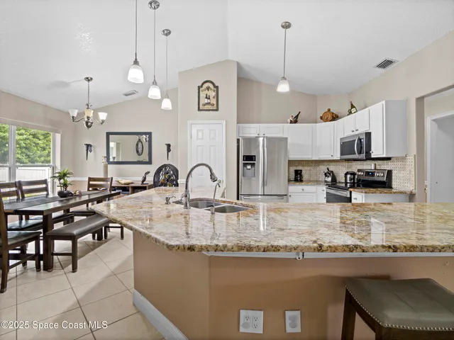 a kitchen with kitchen island granite countertop a table chairs sink and cabinets