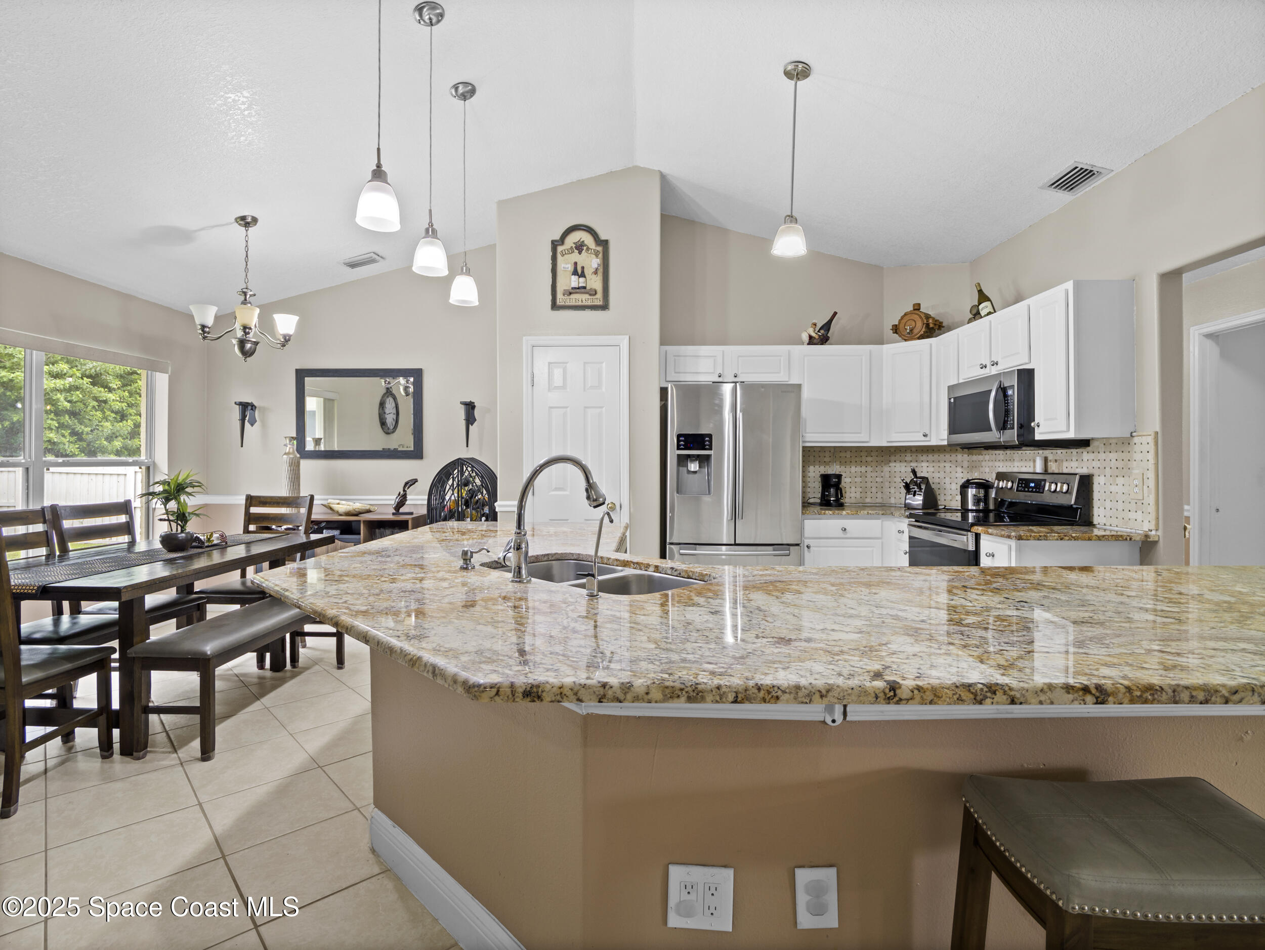 860 Tupelo Road Southwest Palm Bay, FL 32908 - Photo 6 of 26 a kitchen with kitchen island granite countertop a table chairs sink and cabinets