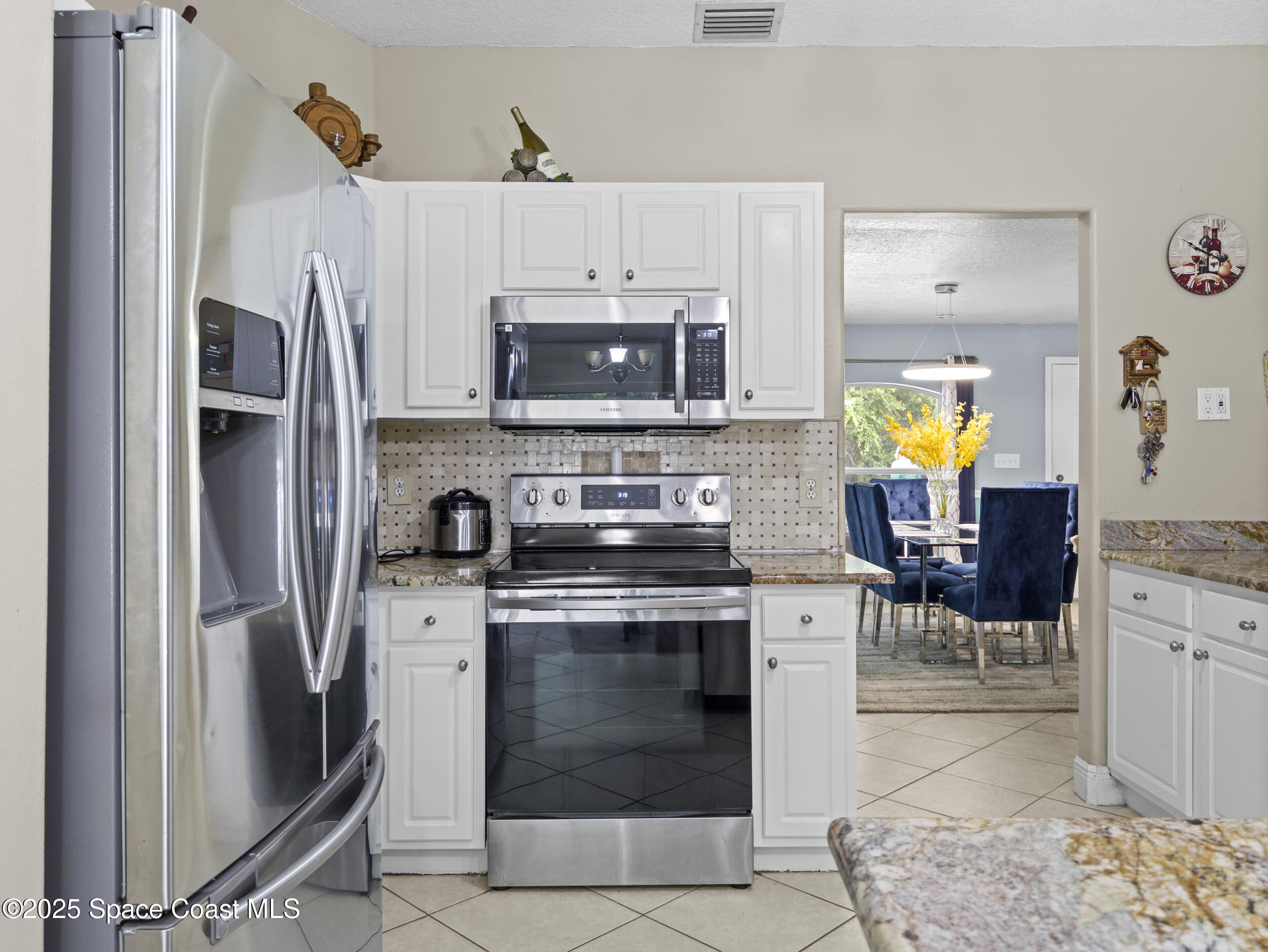 860 Tupelo Road Southwest Palm Bay, FL 32908 - Photo 8 of 26 a kitchen with stainless steel appliances granite countertop a stove refrigerator and a microwave