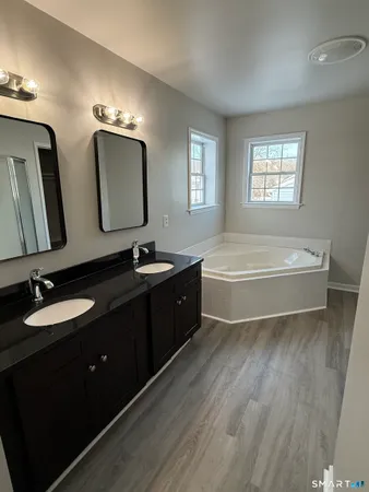 a spacious bathroom with a bathtub double sink and mirror