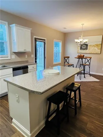 a kitchen with stainless steel appliances granite countertop a dining table chairs and wooden floor