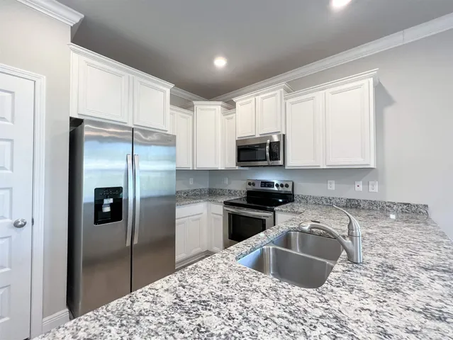a kitchen with stainless steel appliances granite countertop a refrigerator sink and stove