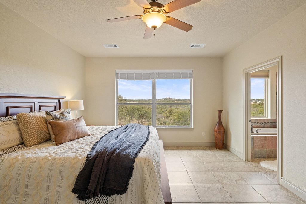 232 Crooked Oak Round Mountain, TX 78663 - Photo 17 of 40 Bedroom with a textured ceiling, light tile patterned floors, ceiling fan, and ensuite bathroom