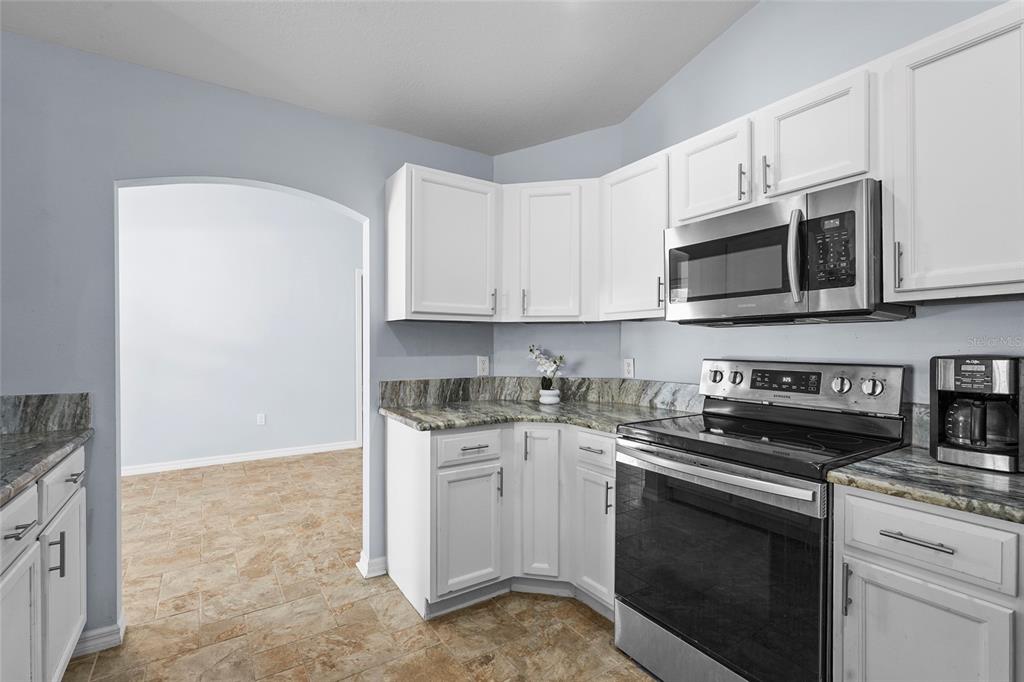 15105 Gulistan Avenue Port Charlotte, FL 33953 - Photo 14 of 39 a kitchen with stainless steel appliances granite countertop a stove a microwave and a white cabinets