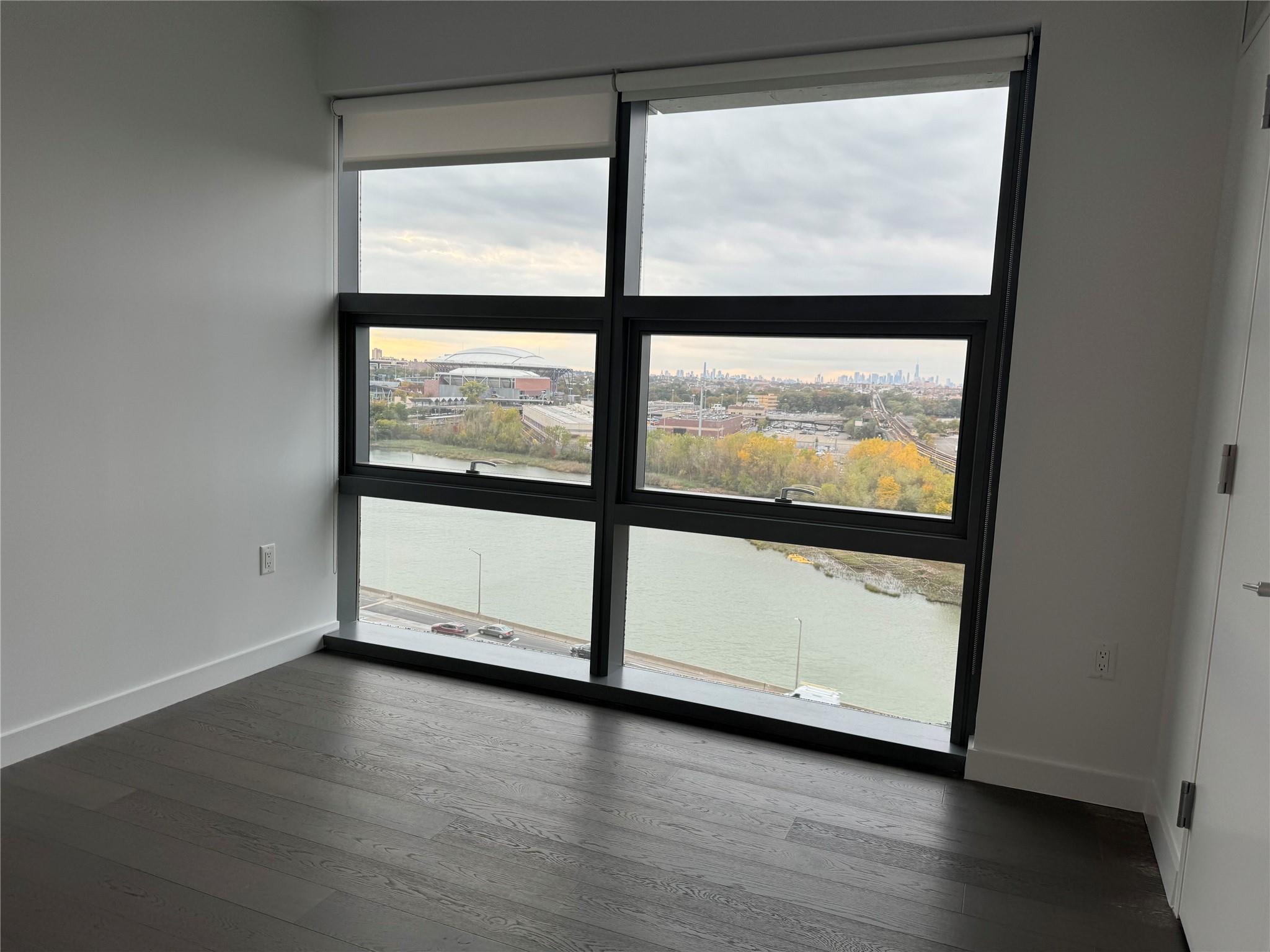 131-01 40 Road, Unit 11M Queens, NY 11354 - Photo 4 of 12 a view of an empty room with wooden floor and a window