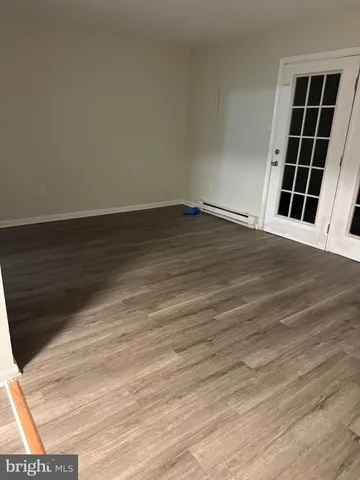 a view of an empty room with wooden floor and windows