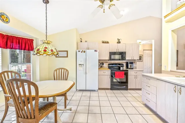 a kitchen with stainless steel appliances granite countertop a dining table chairs and a refrigerator