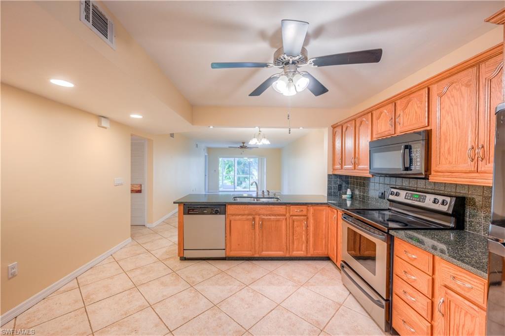 5685 Whitaker Road, Unit C101 Naples, FL 34112 - Photo 2 of 22 a large kitchen with stainless steel appliances granite countertop a stove and a sink with cabinets