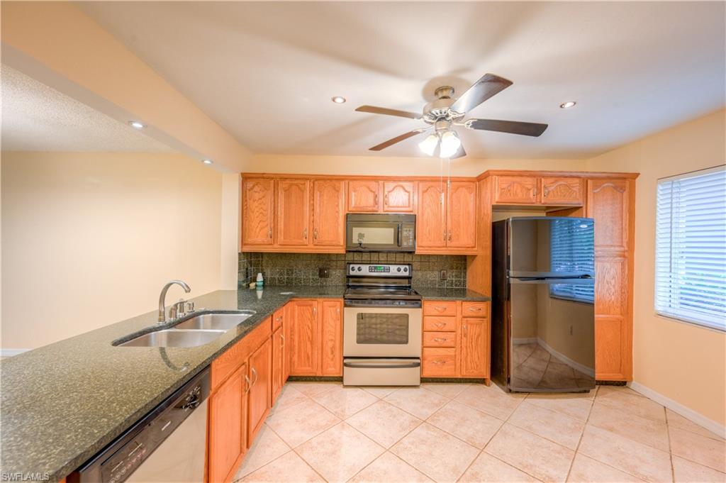5685 Whitaker Road, Unit C101 Naples, FL 34112 - Photo 3 of 22 a kitchen with stainless steel appliances granite countertop a sink a stove and a refrigerator