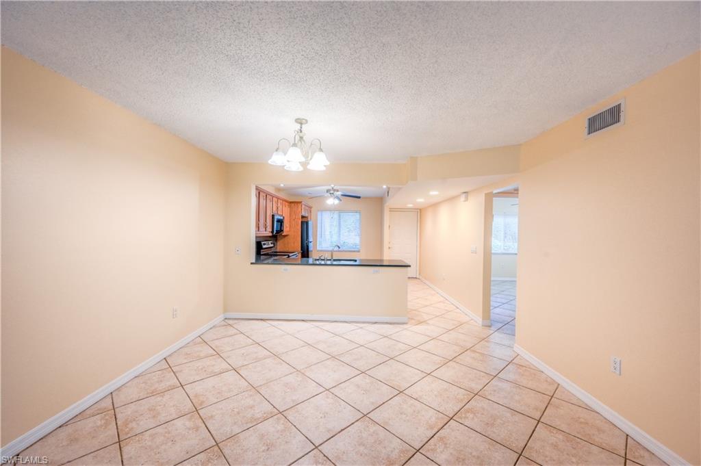 5685 Whitaker Road, Unit C101 Naples, FL 34112 - Photo 8 of 22 a view of a hallway with wooden floor and chandelier