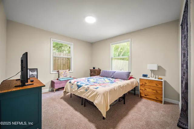 a bedroom with a bed and a flat tv screen on dresser