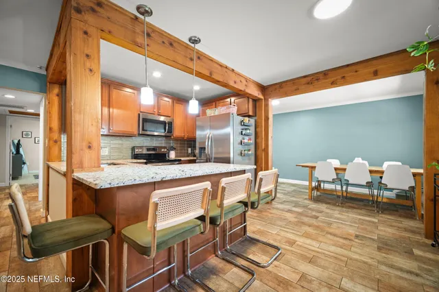 a dining hall with stainless steel appliances kitchen island granite countertop a table and chairs in it
