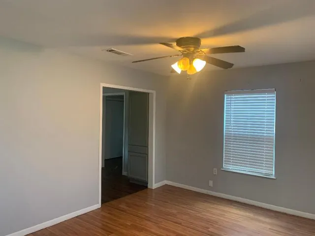 a view of an empty room with window and wooden floor