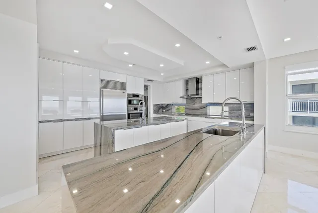 a large white kitchen with a large window and stainless steel appliances