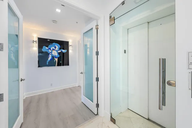 a view of a hallway with wooden floor and paintings on the wall