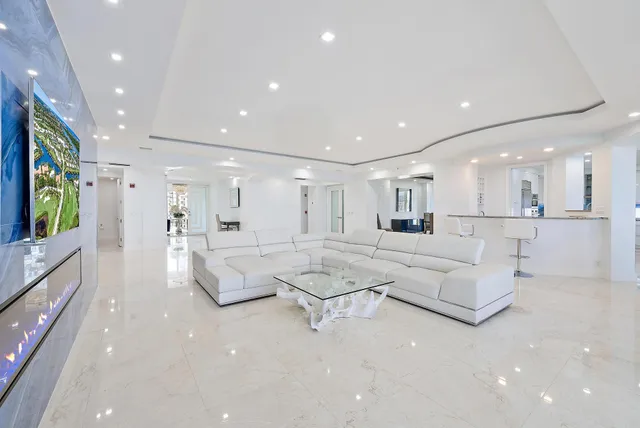 a living room with white couches and white cabinets with wooden floor
