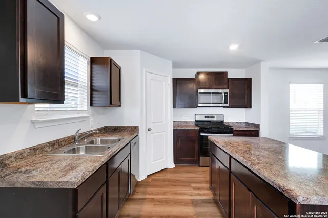 a kitchen with granite countertop kitchen island stainless steel appliances a sink stove and microwave
