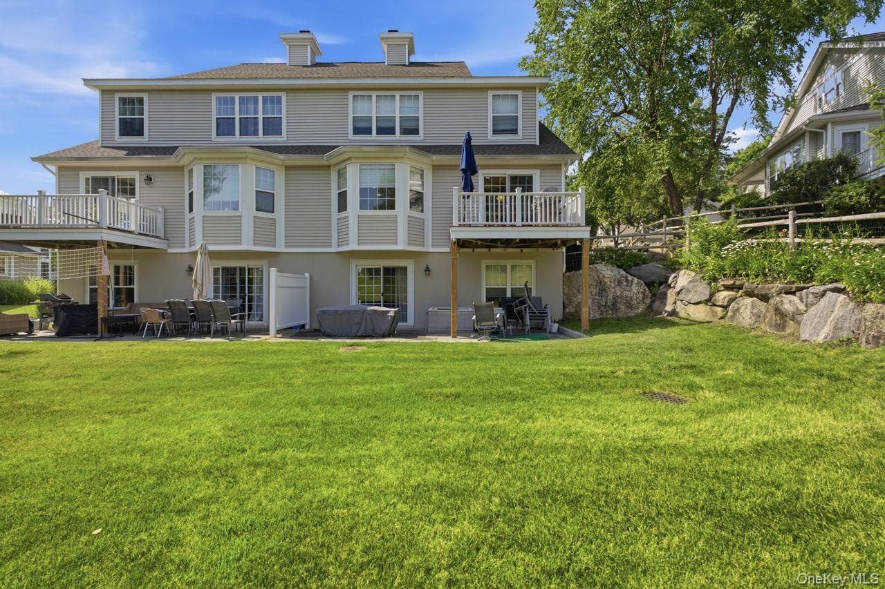 64 Roma Orchard Road Peekskill, NY 10566 - Photo 37 of 40 Spacious rear exterior featuring a large lawn, multiple decks, a ground-level patio, and natural rock landscaping
