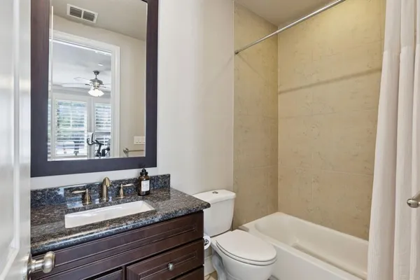 a bathroom with a granite countertop sink toilet a mirror and shower