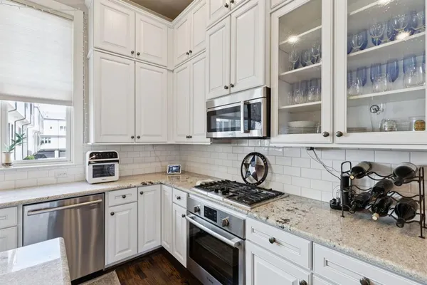 a kitchen with stainless steel appliances white cabinets and a stove top oven