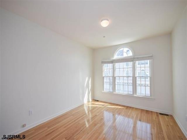 36 Chelsea Court, Unit 36 Atlantic City, NJ 08401 - Photo 7 of 23 an empty room with wooden floor and windows
