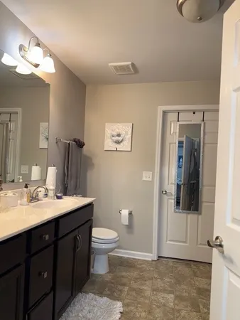 a spacious bathroom with a toilet sink and mirror