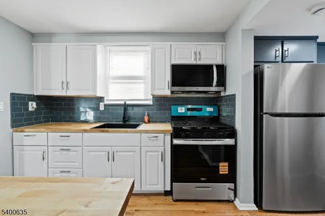 a kitchen with cabinets stainless steel appliances and wooden floor